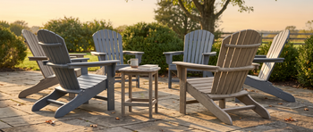 Adirondack chairs in gray and weathered wood finishes arranged around a matching round side table on a stone patio.